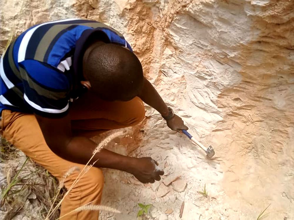 Geologist hammer-sampling a mineral outcrop during a field investigation